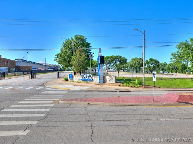 view of street with sidewalks, traffic signs, street lighting, and curbs