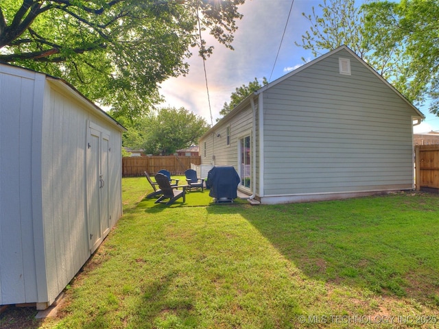exterior space featuring a yard, fence, an outbuilding, and a shed