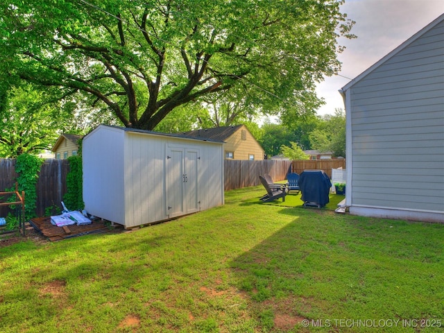 view of yard featuring a storage unit, a fenced backyard, and an outbuilding