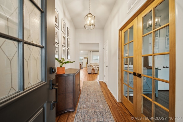 foyer entrance with a notable chandelier, visible vents, dark wood-style floors, and baseboards