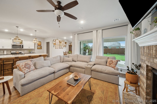 living area featuring a fireplace, recessed lighting, visible vents, and light wood-type flooring