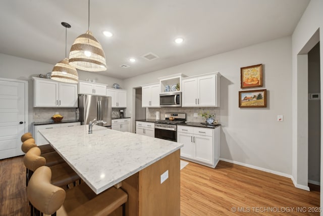 kitchen featuring a breakfast bar area, appliances with stainless steel finishes, tasteful backsplash, open shelves, and baseboards
