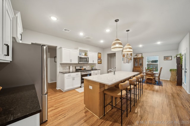 kitchen with open shelves, light wood-style floors, stainless steel appliances, white cabinetry, and visible vents