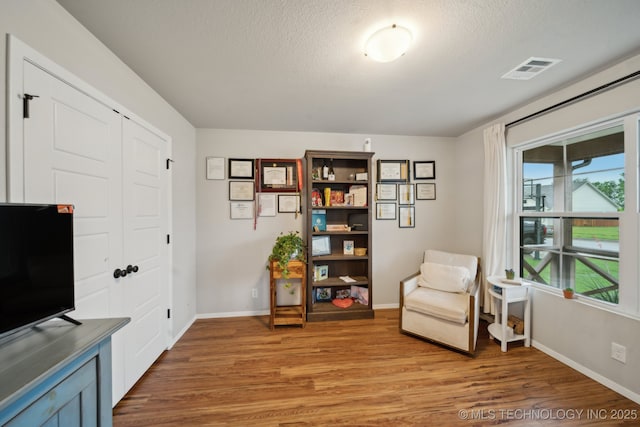 sitting room with baseboards, visible vents, and light wood-style floors