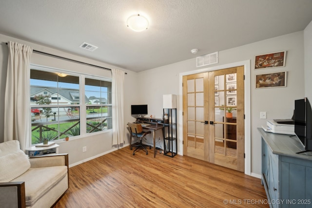 office featuring baseboards, french doors, light wood finished floors, and visible vents