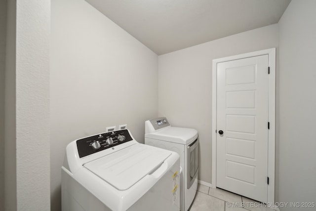 clothes washing area featuring baseboards, laundry area, light tile patterned flooring, and washer and dryer