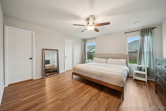 bedroom featuring a ceiling fan, baseboards, visible vents, and light wood-style flooring