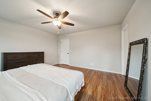 bedroom with a ceiling fan, baseboards, visible vents, and wood finished floors