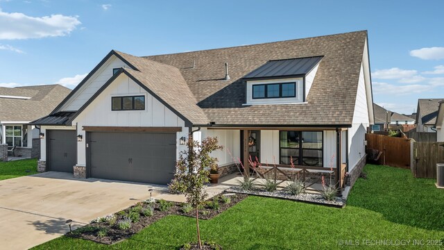 view of front facade featuring a front lawn, fence, covered porch, board and batten siding, and driveway