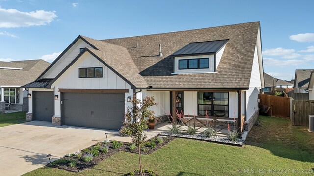 view of front of property with covered porch, board and batten siding, driveway, a front yard, and fence