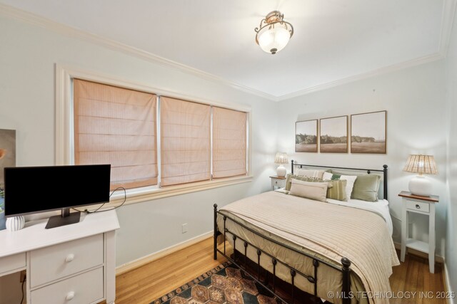 bedroom featuring baseboards, ornamental molding, and wood finished floors