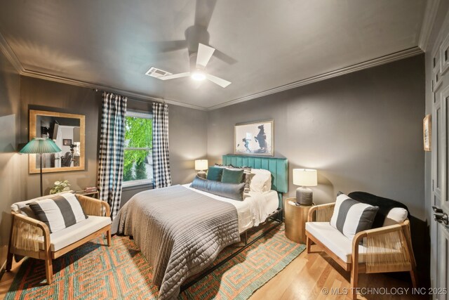 bedroom with visible vents, a ceiling fan, crown molding, and wood finished floors