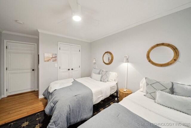 bedroom featuring a closet, ornamental molding, wood finished floors, baseboards, and ceiling fan