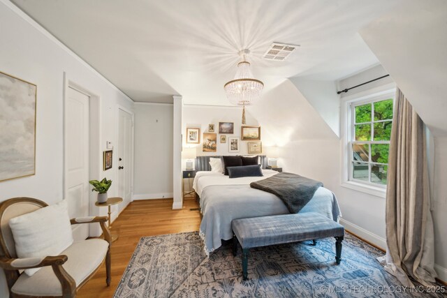 bedroom with a chandelier, baseboards, visible vents, and wood finished floors