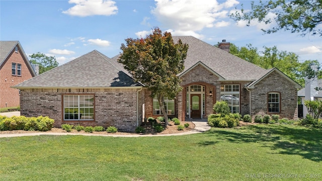 9219 N 134th E Ave, Owasso, OK 74055 - french country home featuring brick siding, a chimney, a shingled roof, and a front lawn