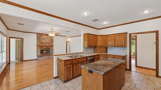 9219 N 134th E Ave, Owasso, OK 74055 - kitchen featuring a sink, brown cabinets, a brick fireplace, dishwasher, and crown molding