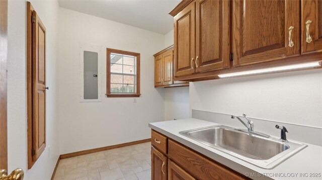 9219 N 134th E Ave, Owasso, OK 74055 - kitchen with a sink, brown cabinets, electric panel, light countertops, and baseboards