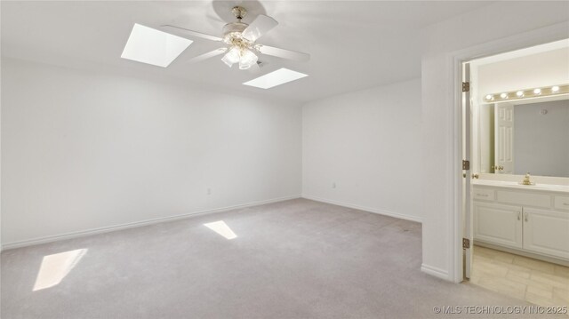 9219 N 134th E Ave, Owasso, OK 74055 - unfurnished bedroom with a skylight, light colored carpet, a sink, ensuite bath, and baseboards
