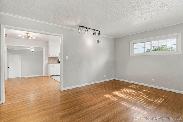 unfurnished room with visible vents, ornamental molding, a textured ceiling, light wood finished floors, and a notable chandelier