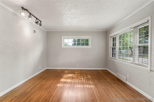 spare room featuring visible vents, a textured wall, baseboards, and hardwood / wood-style flooring
