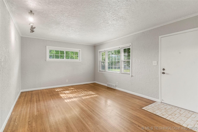 empty room with visible vents, crown molding, a textured wall, hardwood / wood-style floors, and a textured ceiling