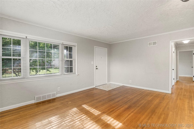 spare room featuring wood finished floors, a textured ceiling, and visible vents