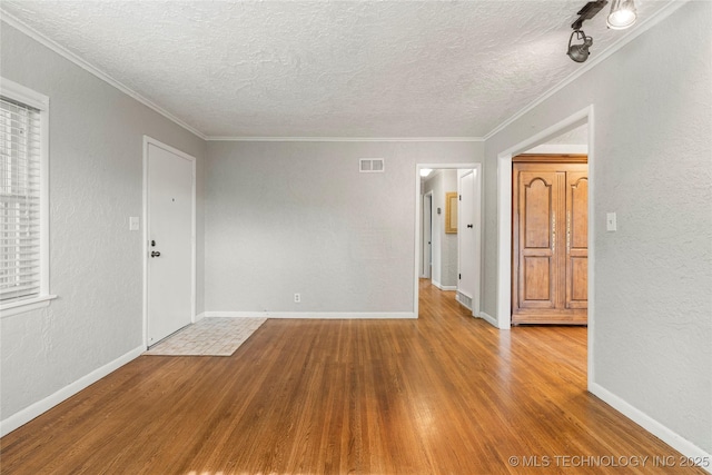 interior space featuring crown molding, a textured ceiling, wood finished floors, and visible vents