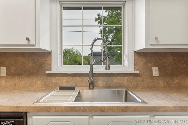 room details with a sink, light countertops, decorative backsplash, and white cabinetry