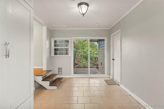 doorway to outside featuring crown molding, light tile patterned flooring, and baseboards