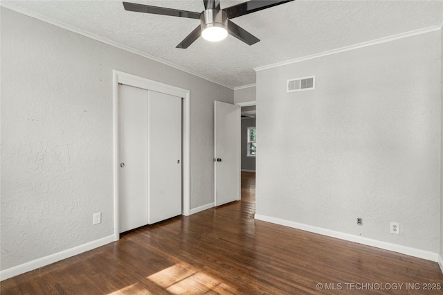 unfurnished bedroom with visible vents, crown molding, a closet, wood finished floors, and a textured ceiling