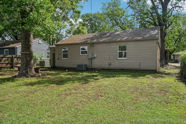 rear view of property with a fenced backyard, central air condition unit, a yard, and crawl space