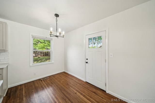 unfurnished dining area with baseboards, a notable chandelier, wood finished floors, and a healthy amount of sunlight