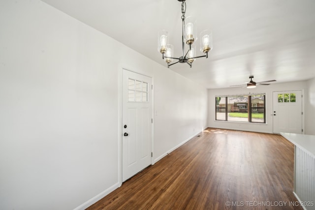 interior space with baseboards, ceiling fan with notable chandelier, and wood finished floors