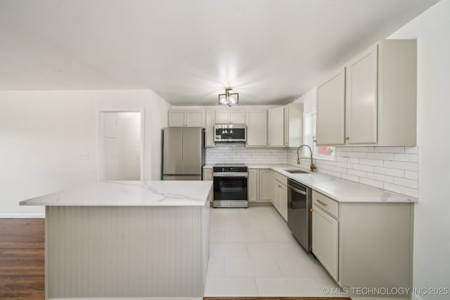 kitchen with a sink, tasteful backsplash, light stone countertops, and stainless steel appliances