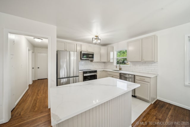 kitchen with decorative backsplash, appliances with stainless steel finishes, a sink, baseboards, and light wood finished floors