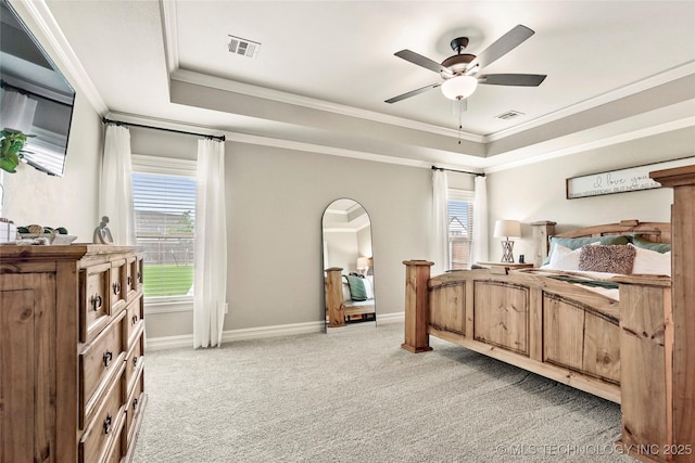 bedroom with a tray ceiling, visible vents, and multiple windows