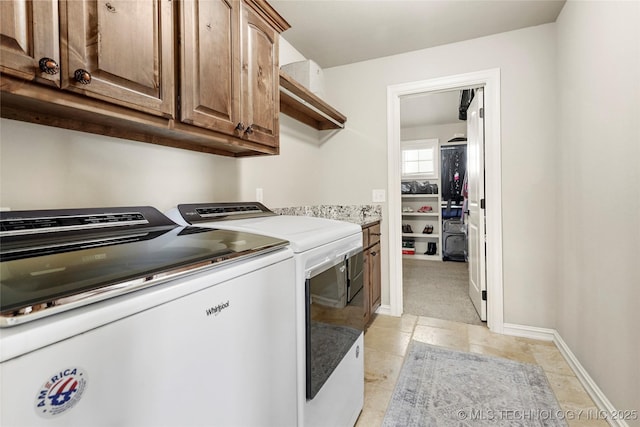 laundry area with washing machine and clothes dryer, baseboards, and cabinet space
