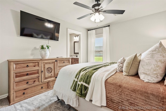 bedroom with connected bathroom, a ceiling fan, and light colored carpet