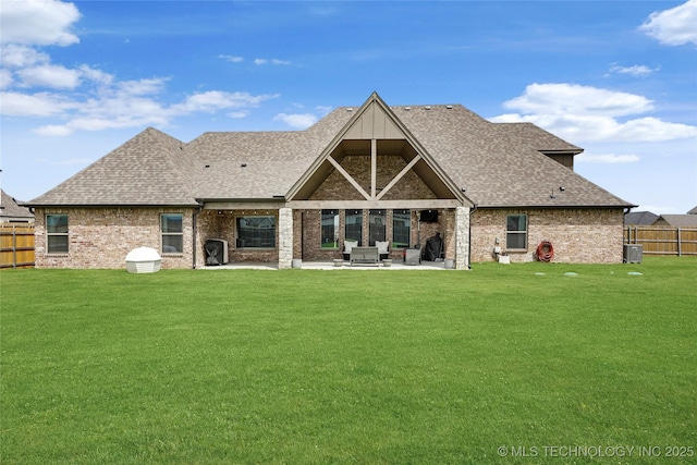 rear view of house featuring a patio area, brick siding, a fenced backyard, a yard, and a shingled roof