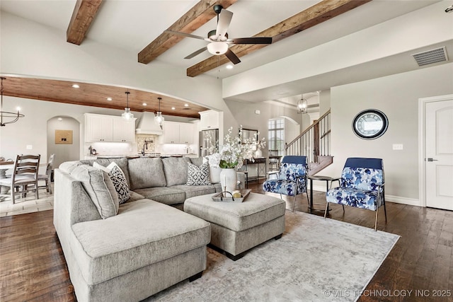 living area featuring dark wood-style flooring, arched walkways, recessed lighting, and ceiling fan with notable chandelier