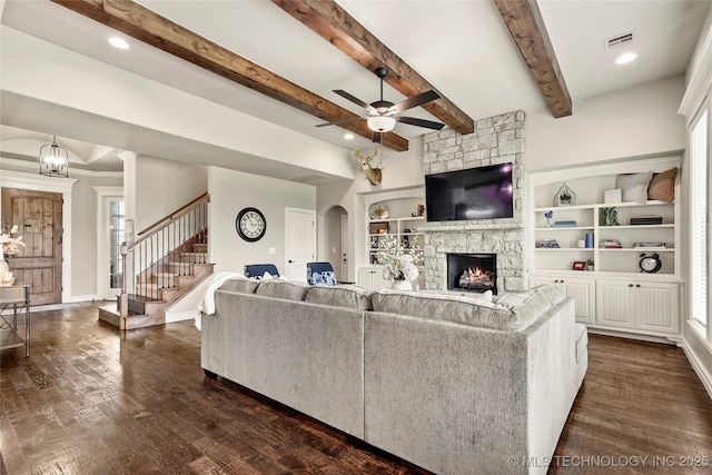 living area featuring dark wood-style flooring, a fireplace, stairs, a ceiling fan, and visible vents