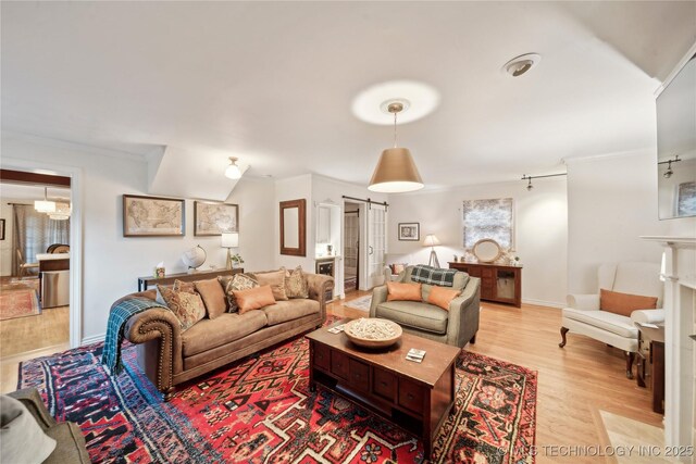 2252 S Troost Ave, Tulsa, OK 74114 - living area with baseboards, ornamental molding, light wood finished floors, and a barn door