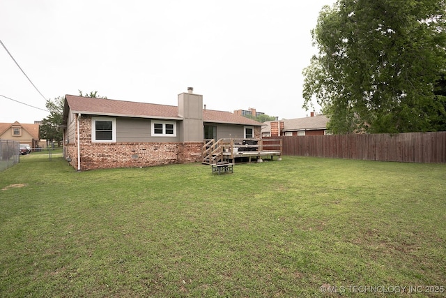 rear view of property featuring a fenced backyard, a chimney, a lawn, and brick siding