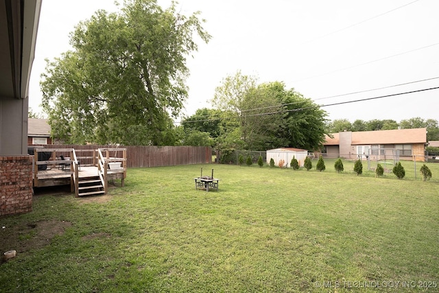 view of yard featuring a fenced backyard, an outdoor fire pit, and a deck