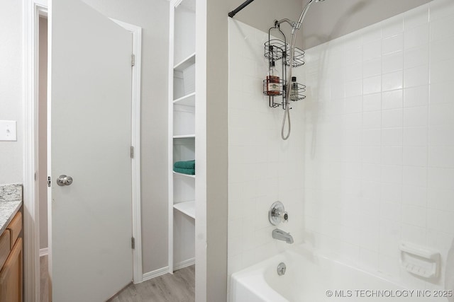 full bath with baseboards, washtub / shower combination, wood finished floors, and vanity