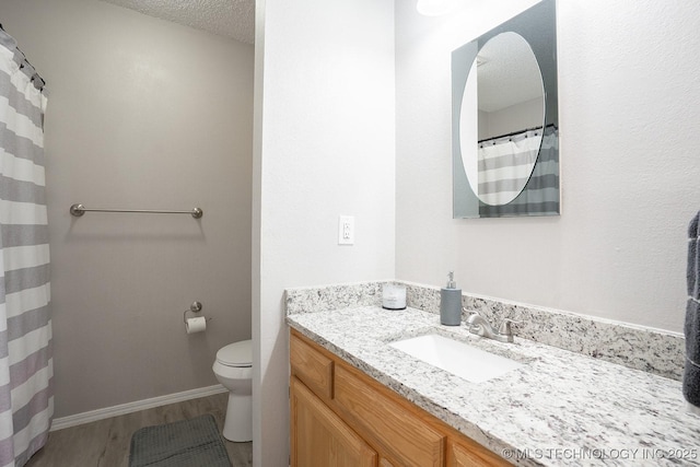 full bath featuring vanity, wood finished floors, toilet, baseboards, and a textured ceiling