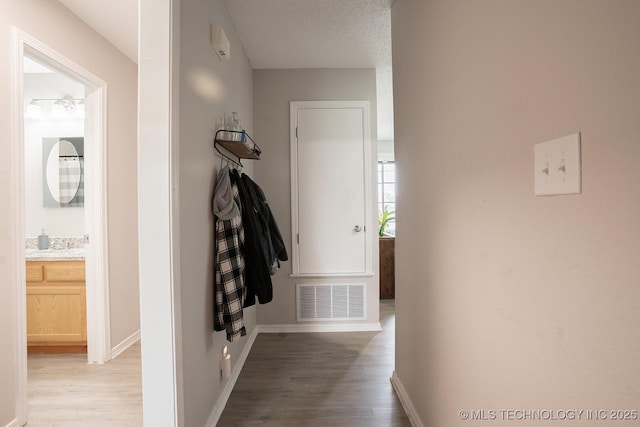 corridor with visible vents, baseboards, and light wood-type flooring