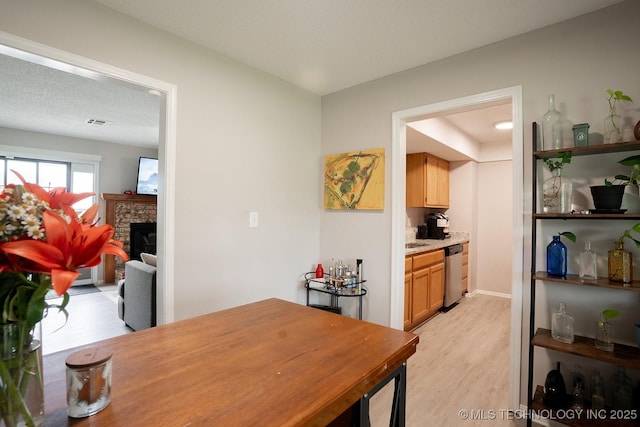 dining room featuring light wood-style floors, a fireplace, and visible vents