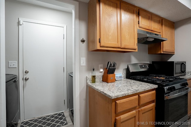 kitchen with light stone countertops, black range with gas stovetop, washing machine and dryer, and under cabinet range hood