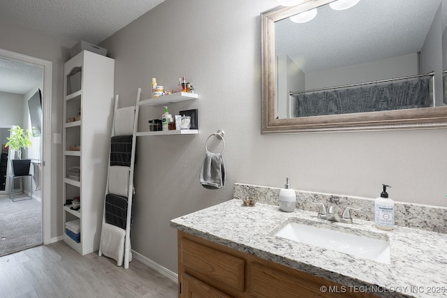 bathroom with vanity, wood finished floors, baseboards, a textured ceiling, and a shower with curtain